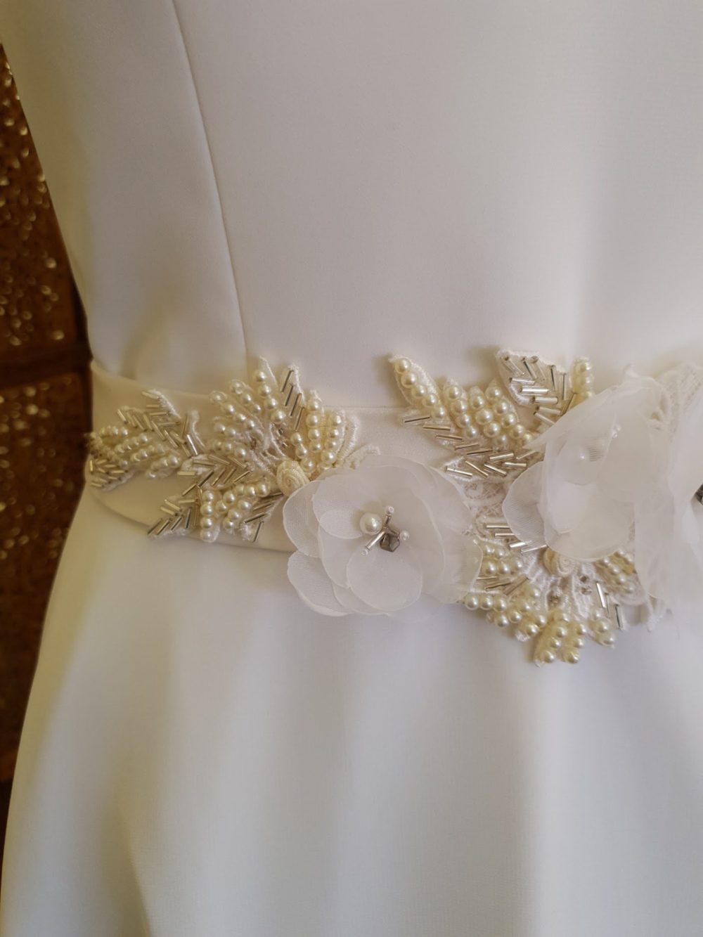 Håndlavet brudebælte af Karina Bentzen med blomster og blonder dekoreret med perler. Satinbåndet er ca. 5 cm bredt. De fleste materialer er genanvendt fra udgået brudekjoler. 