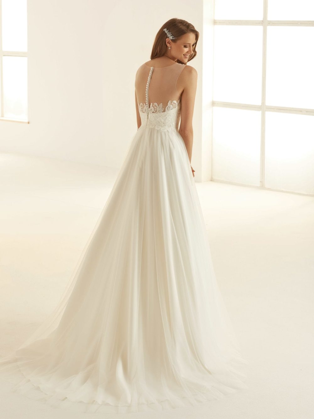 Bianco Evento. Model Atessa er er smuk brudekjole med tylskørt og illusionen af hjerteudskæring og bar ryg. Kjolen har blonder på overkroppen der er dekoreret med hvide perler.