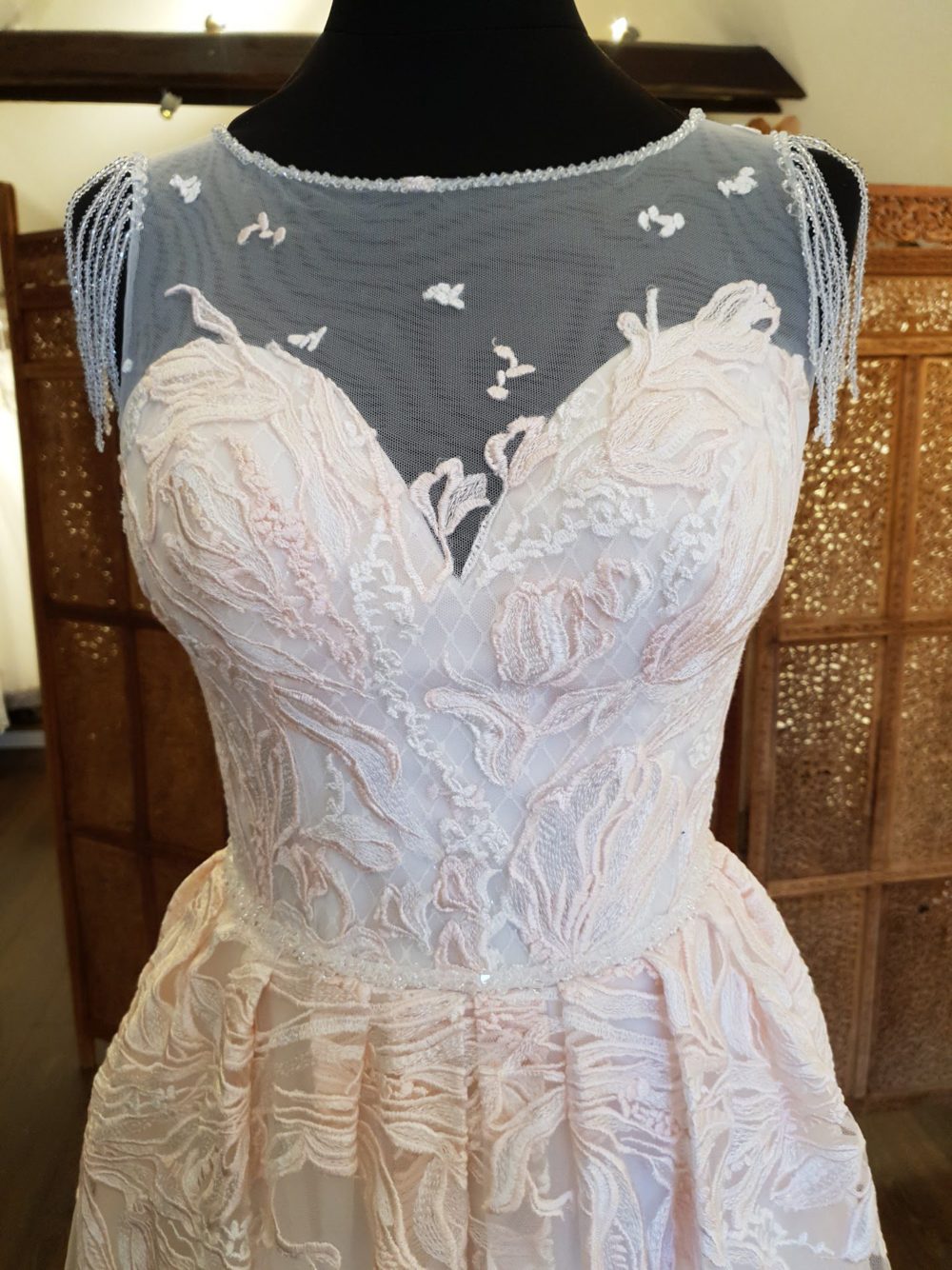 Daria Karlozi. Model Lunaria. Dekorativ A-line brudekjole med lyserøde blondeapplikationer og perler. Kjolen har illusionen af hjerteudskæring og key-holeryg.