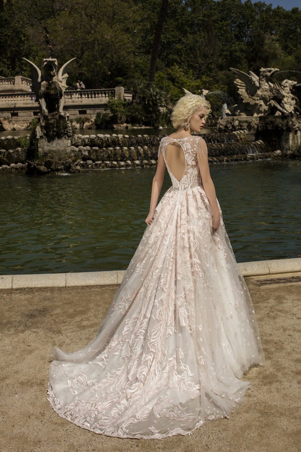 Daria Karlozi. Model Lunaria. Dekorativ A-line brudekjole med lyserøde blondeapplikationer og perler. Kjolen har illusionen af hjerteudskæring og key-holeryg.