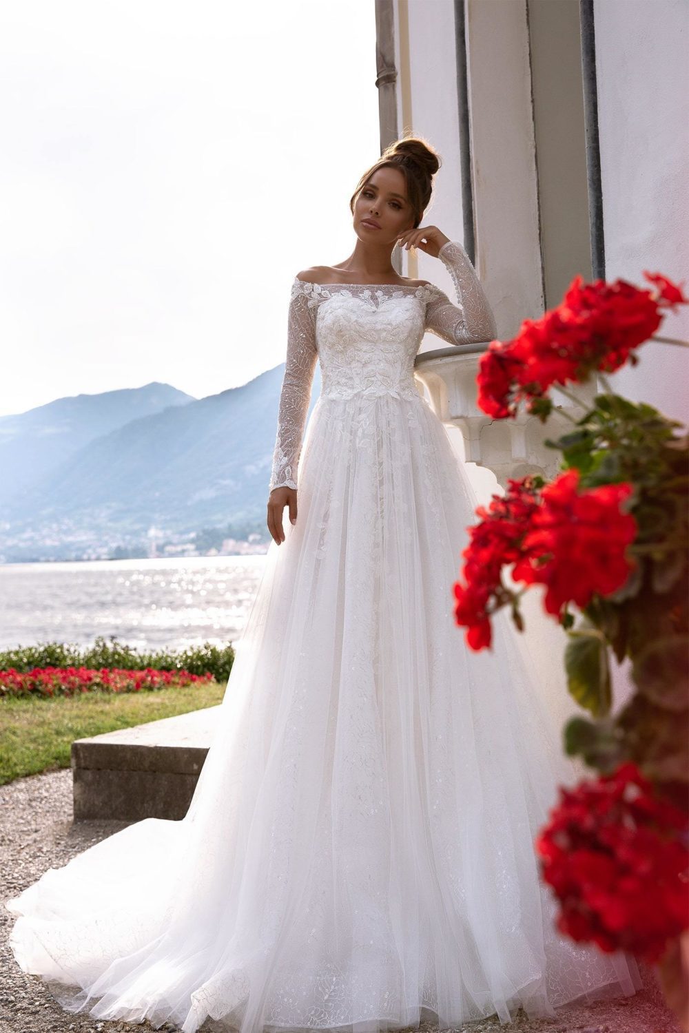 Maria Anette - Model 5016. A-line brudekjole med lange ærmer og bådudskæring. Kjolen har en blonde med sølvtråd og er desuden dekoreret med perlebroderi af blade og blomster.
