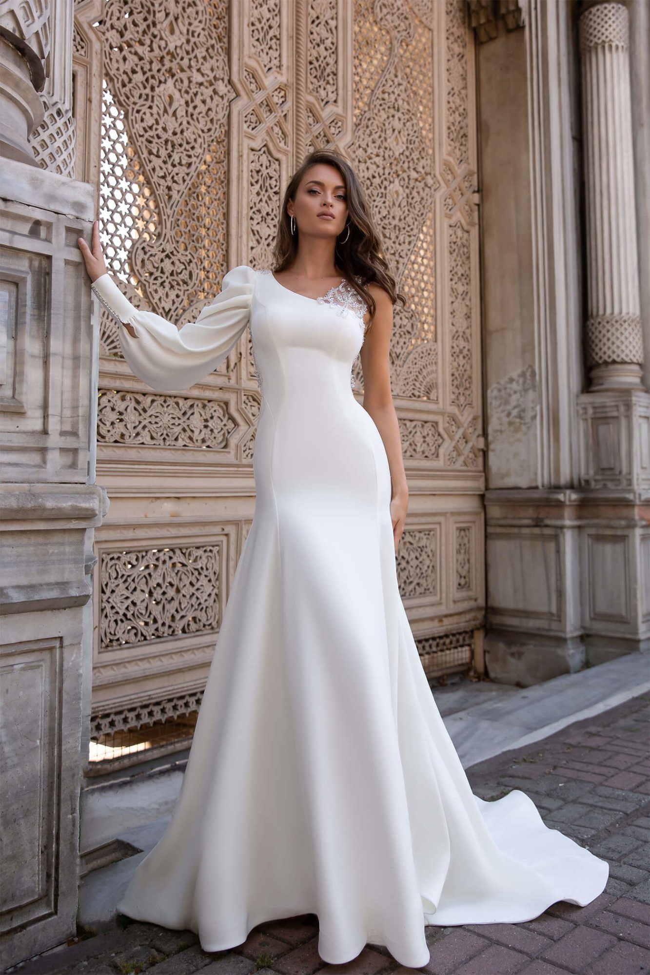 Maria Anette - Model 5218. Slank og enkel brudekjole i satin, med et enkelt langt ærme og en yderst smuk og dekorativ perleryg som går op og danne strop på den ene skulder.