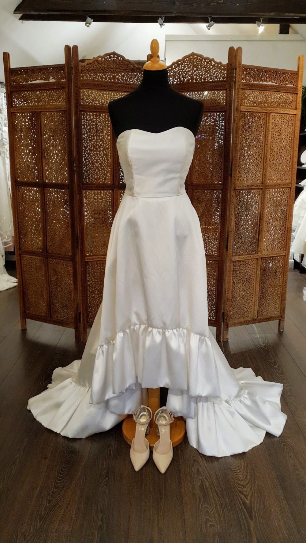 Virkelig smuk og enkel pre-loved brudekjole fra Halfpenny London. Kjolen giver dig mulighed for at vise dine smukke ben og stiletter frem med den kortere længde i skørtet foran.