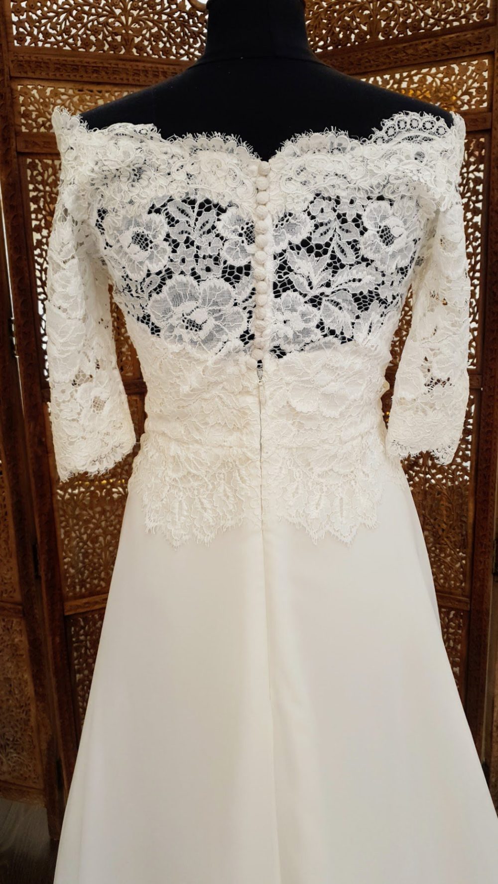 A-line brudekjole i chiffon med blonder på overkroppen der danner bådudskræing og giver kjolen 3/4 lange ærmer.