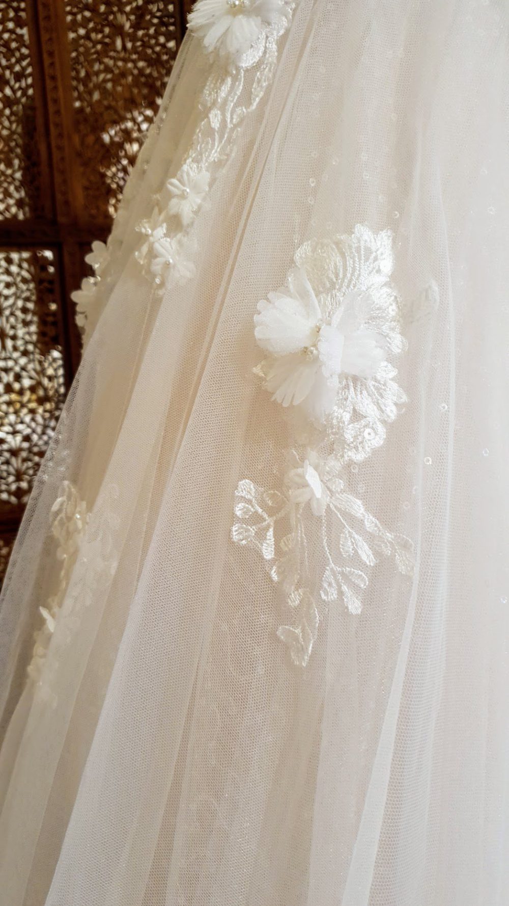 Karim Design. Smuk A-line brudekjole med dyb v-udskæring både foran og bagpå. Kjolen er dekoreret med blomster der har 3D effekt.