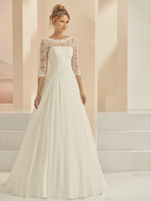 Bianco Evento. Model Cecile. A- line brudekjole med blonder og skørt i chiffon. Kjolen har bådudskæring 3/4 lange ærmer og v-udskæring på ryggen med snørelukning.