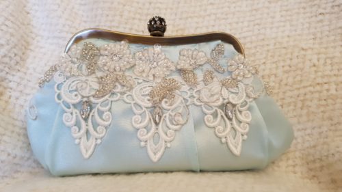 Smuk lyseblå re-designet clutch, med pyntede blondeapplikationer på fronten og lang tilhørende kæde som skulderrem.