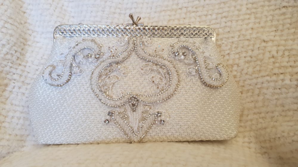 Smuk re-designet taske af Karina Bentzen i vintage stil. Tasken er Ivory med sølvtråd. Fronten er pyntet med blondeapplikationr og masser af perler og sten.