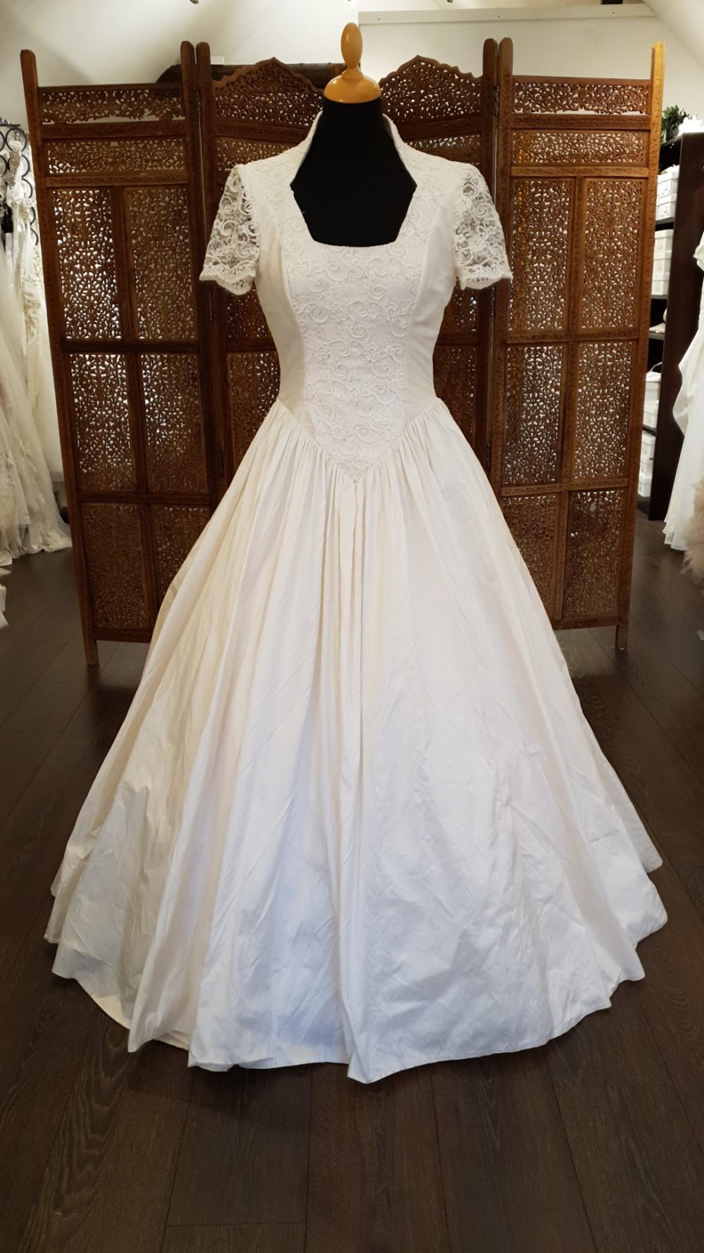 Karim Design. Smuk pre-loved A-line brudekjole i vintage stil. Kjolen er lavet i rå-silke, har smukke blondedetaljer, høj krave og key-hole på ryggen.