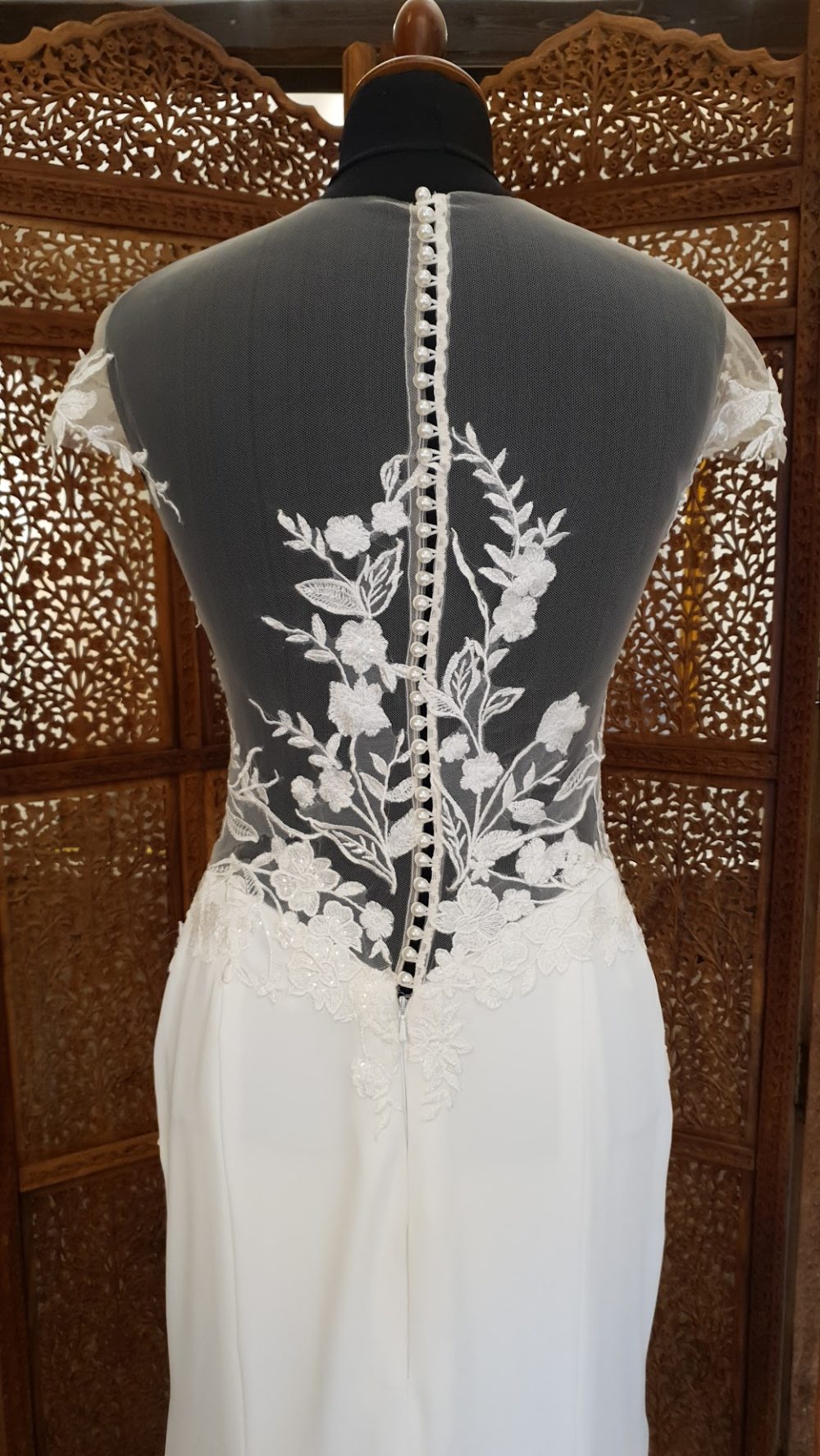 Milan Bride- Smuk fit and flare kjole med meget transparent og dekorativ overkrop. Kjolen har en lukket ryg med tatoo-effekt, små korte ærmer og et glat skørt i crepe med langt slæb.