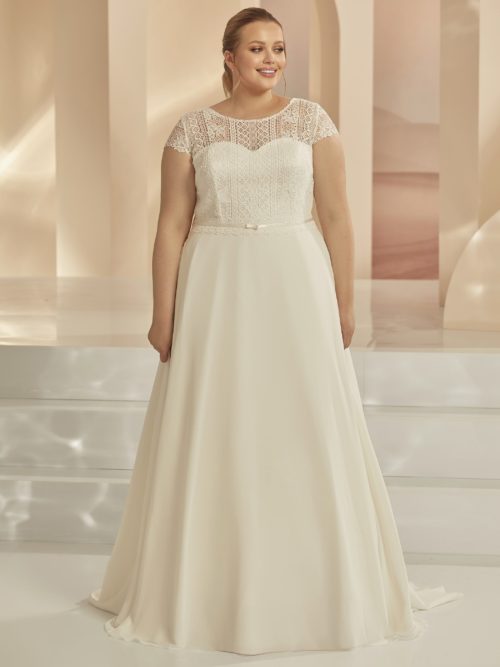 Bianco Evento. Model Ariosa. A-line brudekjole med boho blonder og skørt i satin. Kjolen har illusionen af hjerteudskæring, hvor blonderne går op og danne rund halsudskæring og en lukket ryg med smal key-hole. Derudover er der små korte ærmer.