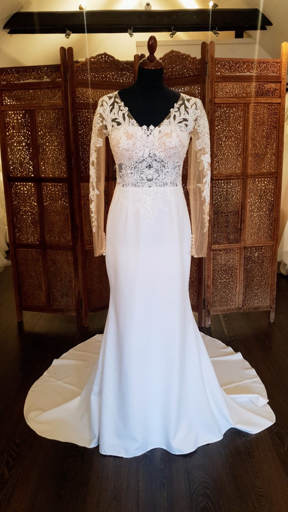 Ladybird. Smuk slank pre-loved brudekjole med et glat skørt og en meget dekorativ overkrop. Kjolen har lange transparente ærmer, v-udksærin og lukket ryg.