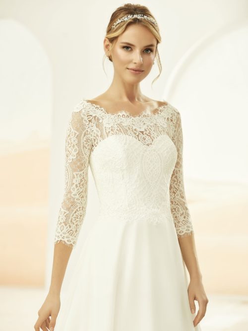 Bianco Evento. Model E-331. Blondebolero med bådudskæring og 3/4 ærmer. Stofbetrukne knapper i ryggen.