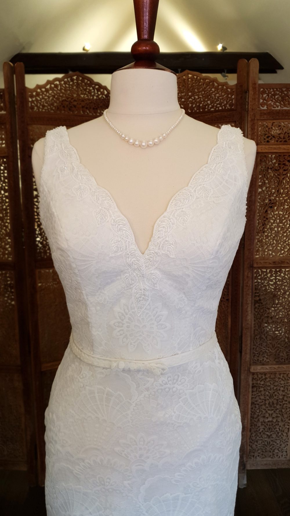 Slank brudekjole med boho-blonder fra top til tå. Kjolen har v-udskæring, brede stropper og et lille slæb.