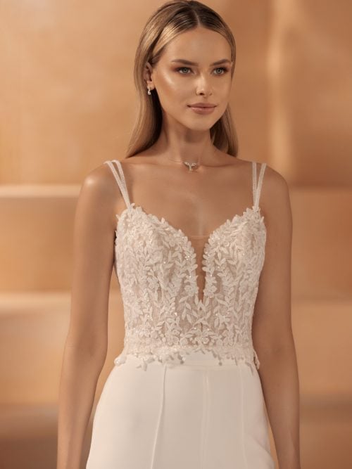 Bianco Evento. Bolero model E-440. Blondebolero med blomster og blade der er dekoreret med perler, pailetter og glitter. Boleroen har dobbelte spagettistropper.