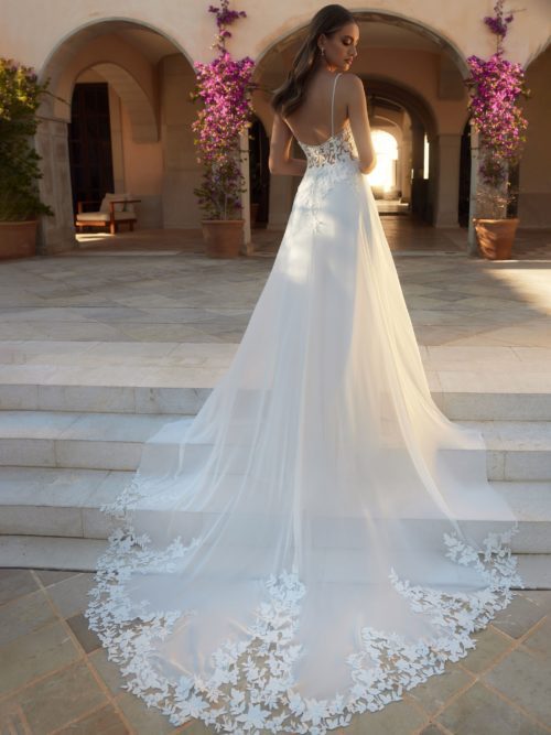 Bianco Evento. Limited Collection. Model Beryl. Smuk, romantisk og ungdommelig A-line brudekjole i chiffon og blonder. Kjolen har tynde spagettistropper og en dyb rygudskæring. Det særlige ved kjolen er den unike og meget smukke slæb som afsluttes med cut-out blondeapplikationer. Blonderne er pyntet med pailetter og perler.
