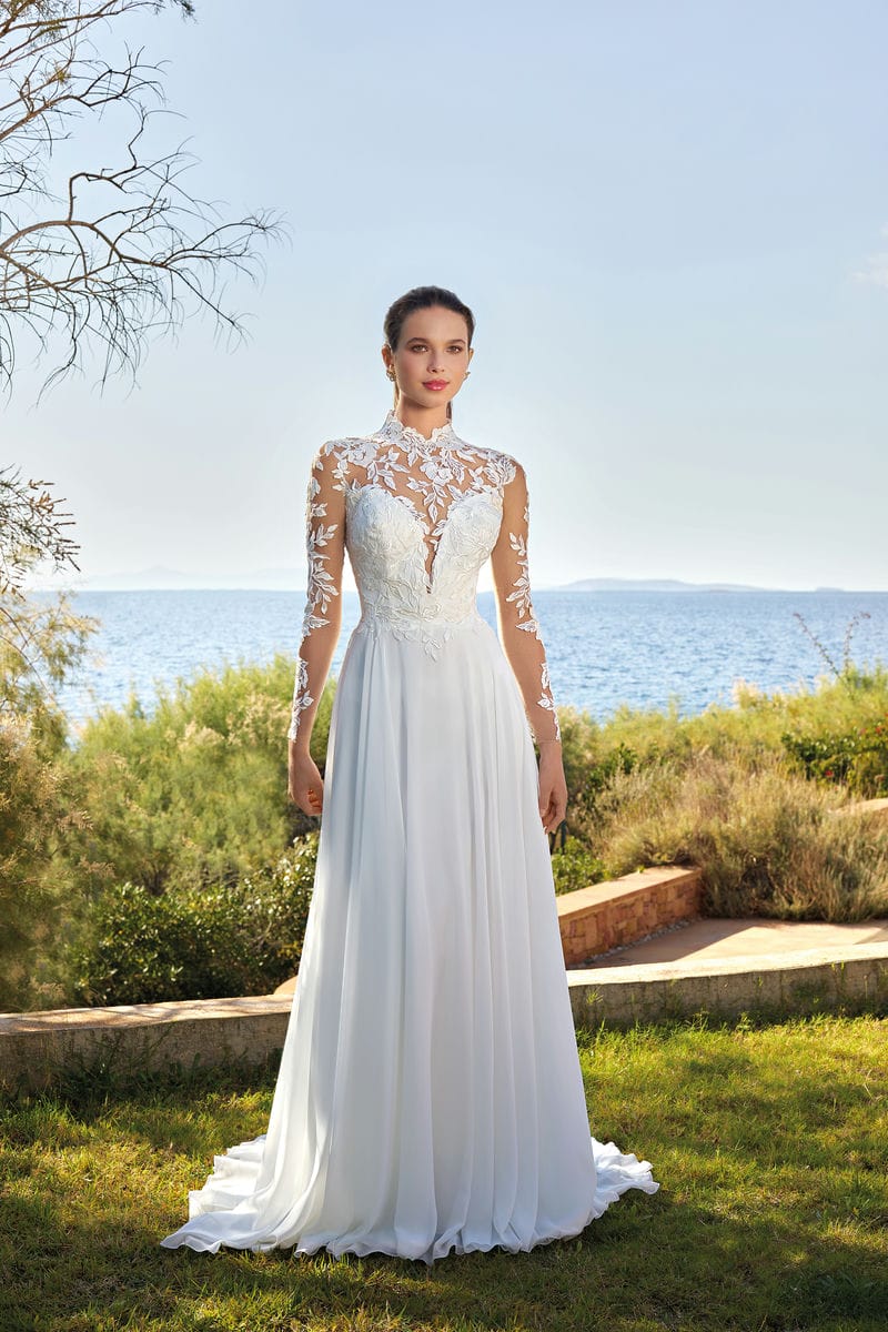 OreaSposa. Model L1103. Smuk A-line brudekjole med dekorative blonder på overkroppen, høj hals, lange ærmer og lukket transparente ærmer. Kjolen har et helt enkelt chiffonskørt med slæb.