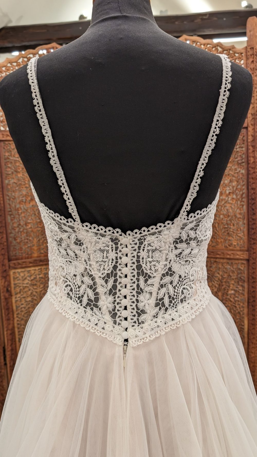 Enzoani. A-line brudekjole med fyldigt tylskørt og smukke grafiske blonder på overkroppen. Kjolen har tynde stroppe, en transparen blonderyg og en nude undertone i tylskørtet.