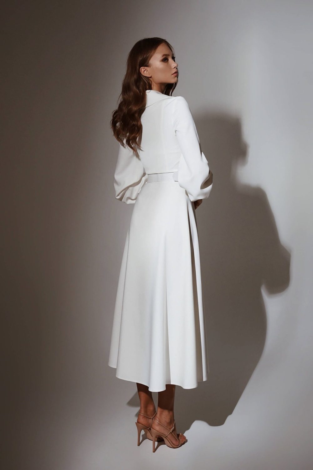 Olya Mak. Model Ava. Enkel og stilfuld kort A-line brudekjole med lange ærmer. Kjolen har krave som på en habitjakke og bælte i taljen.