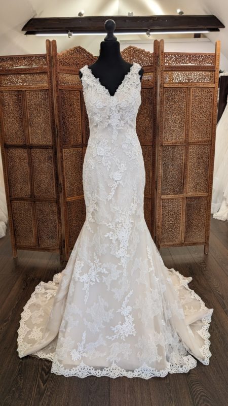 Pronovias. Model Carey. Smuk og romantisk slank brudekjole, med blonder fra top til tå og en super flot ryg. Kjolen har v-udskæring foran og dyb rygudksæring hvor blonderstorpper dekorerer med et stort transparent kryds. Kjolen har en nude bund og en smukt langt slæb.