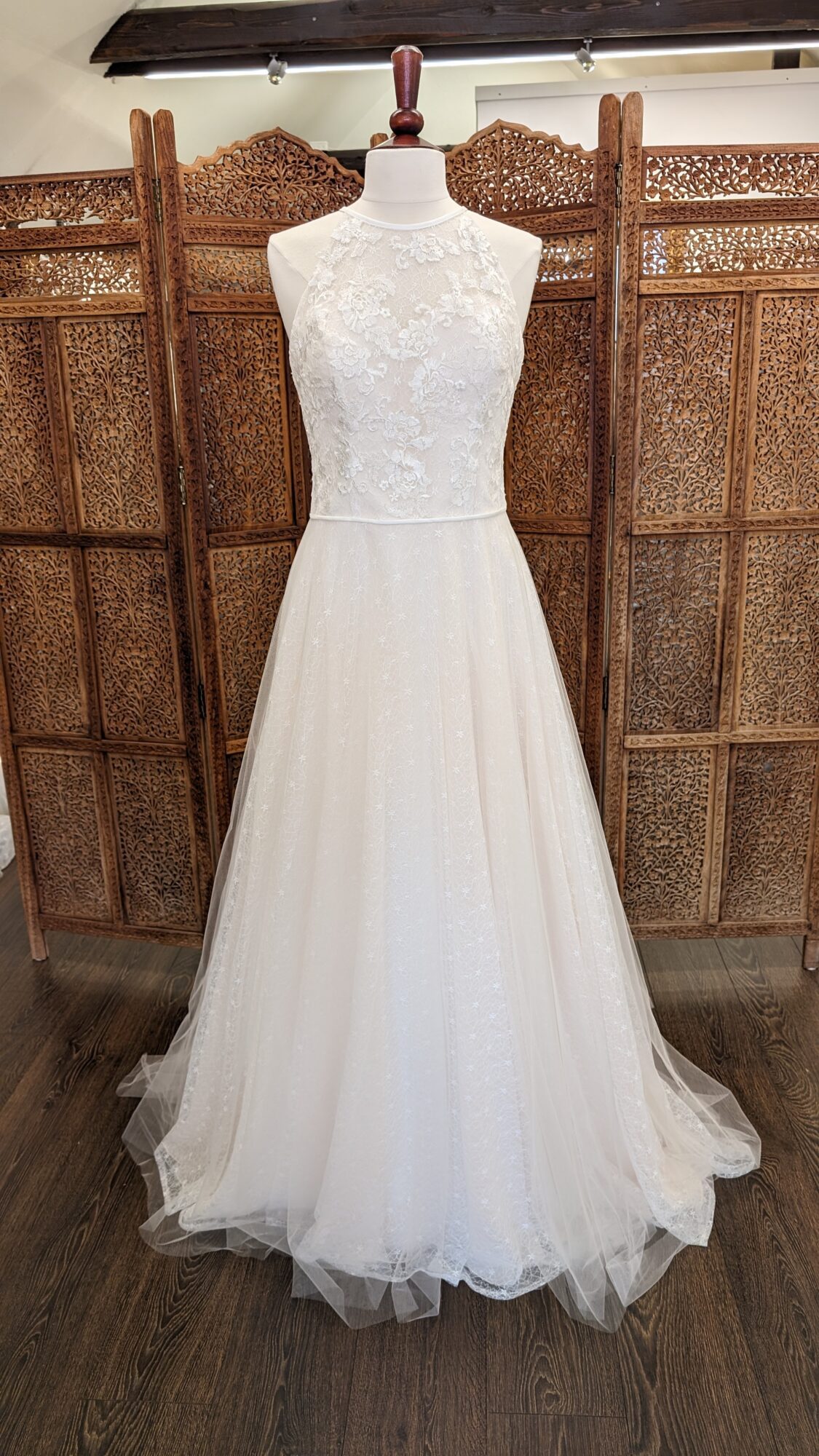 The weddingdress by Marielou. A-line brudekjole i sarte blonde med nude bund. Kjolen har høj halsudskæring både foran og bagpå.