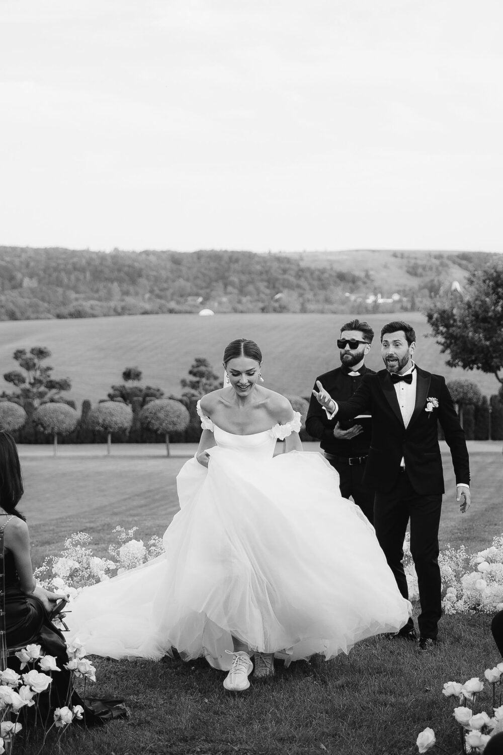 Olya Mak. Model Barry. Smuk, klassisk A-line brudekjole med en lavtaljet corsage i satin og et stort fyldigt tylskørt med langt slæb. Kjolen har off-shoulder stropper dekoreret med blomster og snøre i ryggen.