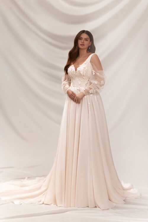 Melory. Model Noemi. Romantisk brudekjole i tyl med brede stropper og lange løse transparente off-shoulder ærmer. Kjolen har en sart peach nuance og er dekoreret med smukke blondere på overkroppen og 3-D blomster.