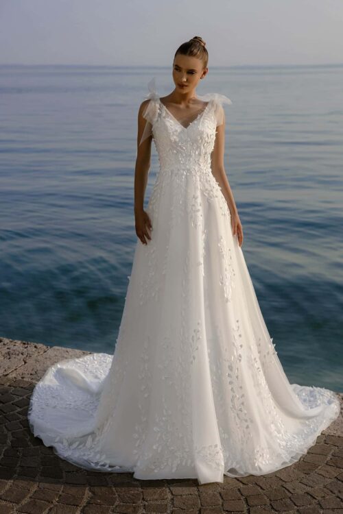 Bella by Eglantine. Model BEL22404. Smuk og romantisk A-line brudekjole i tyl med de smukkeste 3-D blade som dekorerer hele kjolen. Kjolen har brede tylstropper med aftagelige tylsløjfer, en transperent ryg med dyb udskæring og et slot langt slæb.
