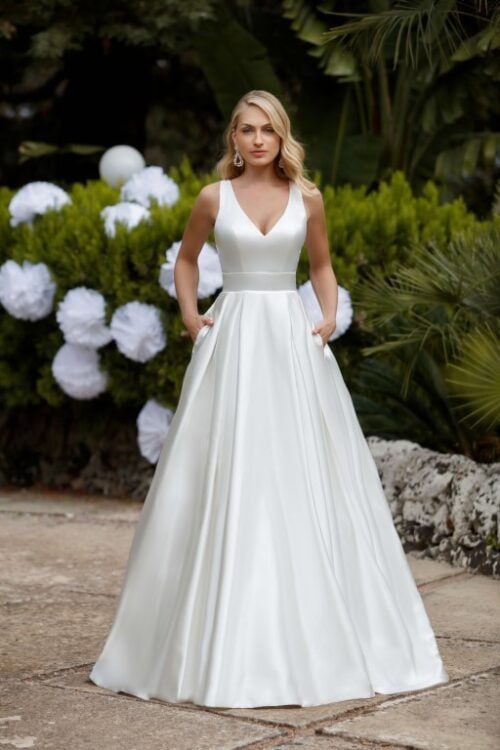 Jarice Bridal. Model Uttara. Klassisk og enkel A-line brudekjole i en smuk skinnende satin. Kjolen har v-udskæring foran, brede stropper der danne kryds på ryggen og lommer.
