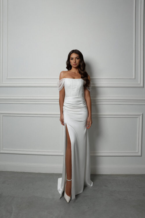 Nevista. Model Alicia. Elegant slank brudekjole i satin med lige skåret corsage og off-shoulder stropper. Kjolen har fine buede linjer og prikket broderinger på overkroppen, som er pyntet med pailetter.