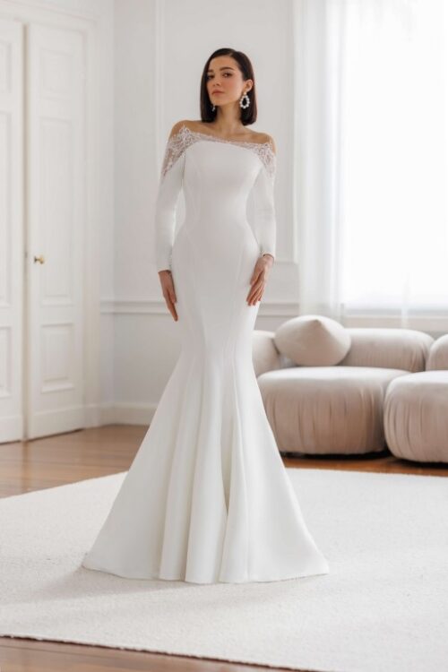 Jarice Bridal. Model Art 26-10. Smuk minimalistisk havfruekjole i Mikado satin med lange ærmer. Kjolen har en blondedetalje som danner bådudskæring, går ned i en spids på armene og danner en smuk lukket og transparent v-udskæring på ryggen.