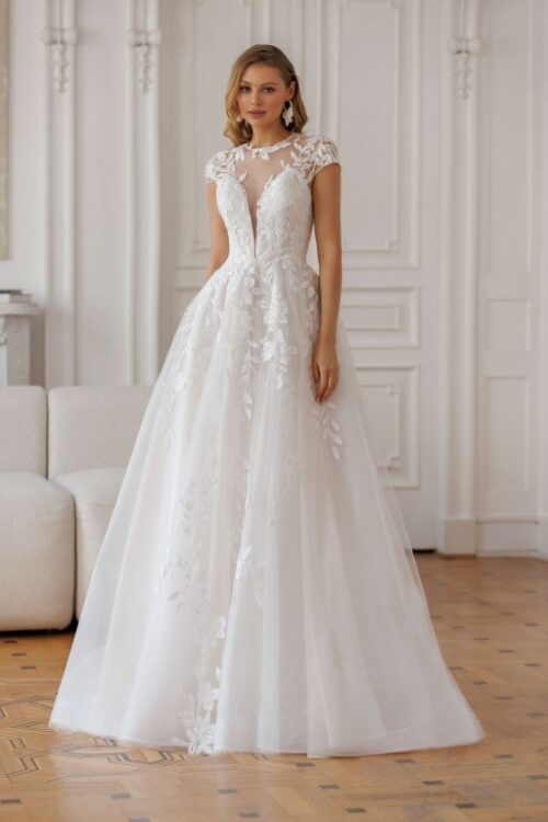 Jarice Bridal. Model Duval. En smuk og romantisk A-line brudekjole i tyl med de smukkeste blonder. Kjolen har en sart nude bundfarve. Den har illussionen af dyb kavalergang men en Ivory mesh som danner rund halsudskæring, små korte ærmer og giver kjolen en smuk og dekorativ transparent v-udskæring på ryggen.
