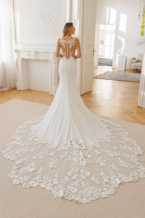 Jarice Bridal. Model Alvina. Smuk slank brudekjole i crepe med cut-outs i siderne på taljen, som har nude mesh og blonder. Kjolen har en lukket men dekorativ transparent ryg i nude mesh med blonder og et helt ekstraordinert smukt slæb.