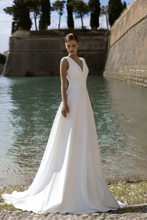 Belle by Eglantine. Model BEL22437. A-line brudekjole i jarquard stof med små tern. Kjolen har brede stropper, v-udskæring både foran og bage, samt en lille krave i halsudskæringen.