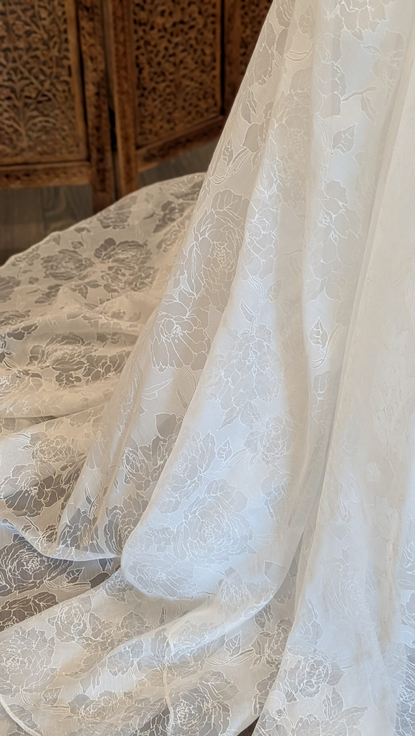Callista. Pre-loved brudekjole i jaquard stof. Kjolen har en drapperet overkrop, brede stropper og v-udskæring både foran og bagpå. Taljeskærringen sidder lavt og der er snøre i ryggen, som gør kjolen mere fleksibel i størrelsen. Det lille element af rhinsten i taljen kan nemt fjernes. Slæbet er ikke så langt.