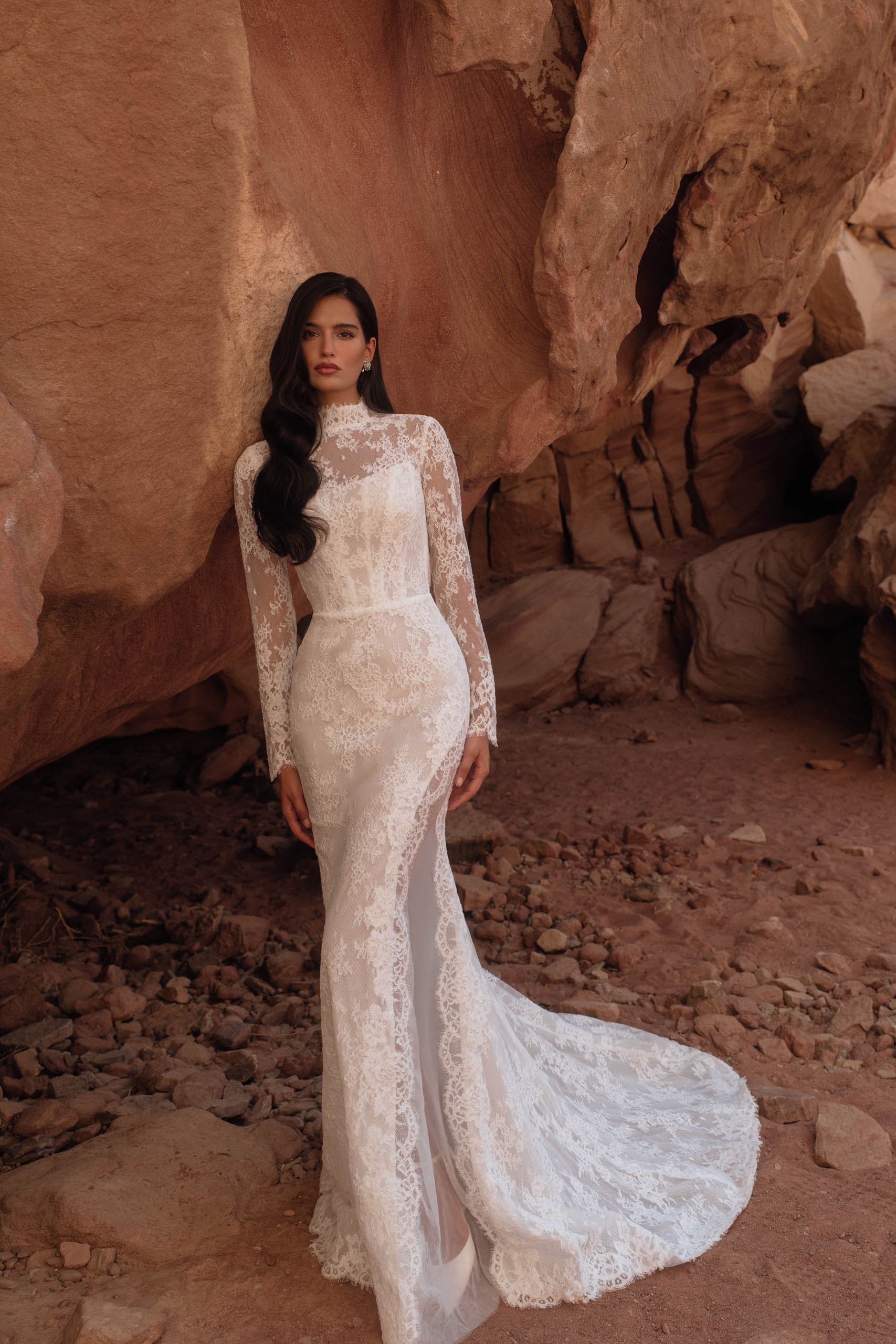 Katy Corso. Mdel Edvina Simple. Elegant og sexet helblondekjole med lange ærmer og høj hals. Kjolen har en transparent udtryk med en høj see through cut out på ydersiden af benet og helt op til hoften som giver et helt særligt look. Corsagen har stivere og cat eye udskæring under de smykke blonder. Ryggen har et stort key-hole.