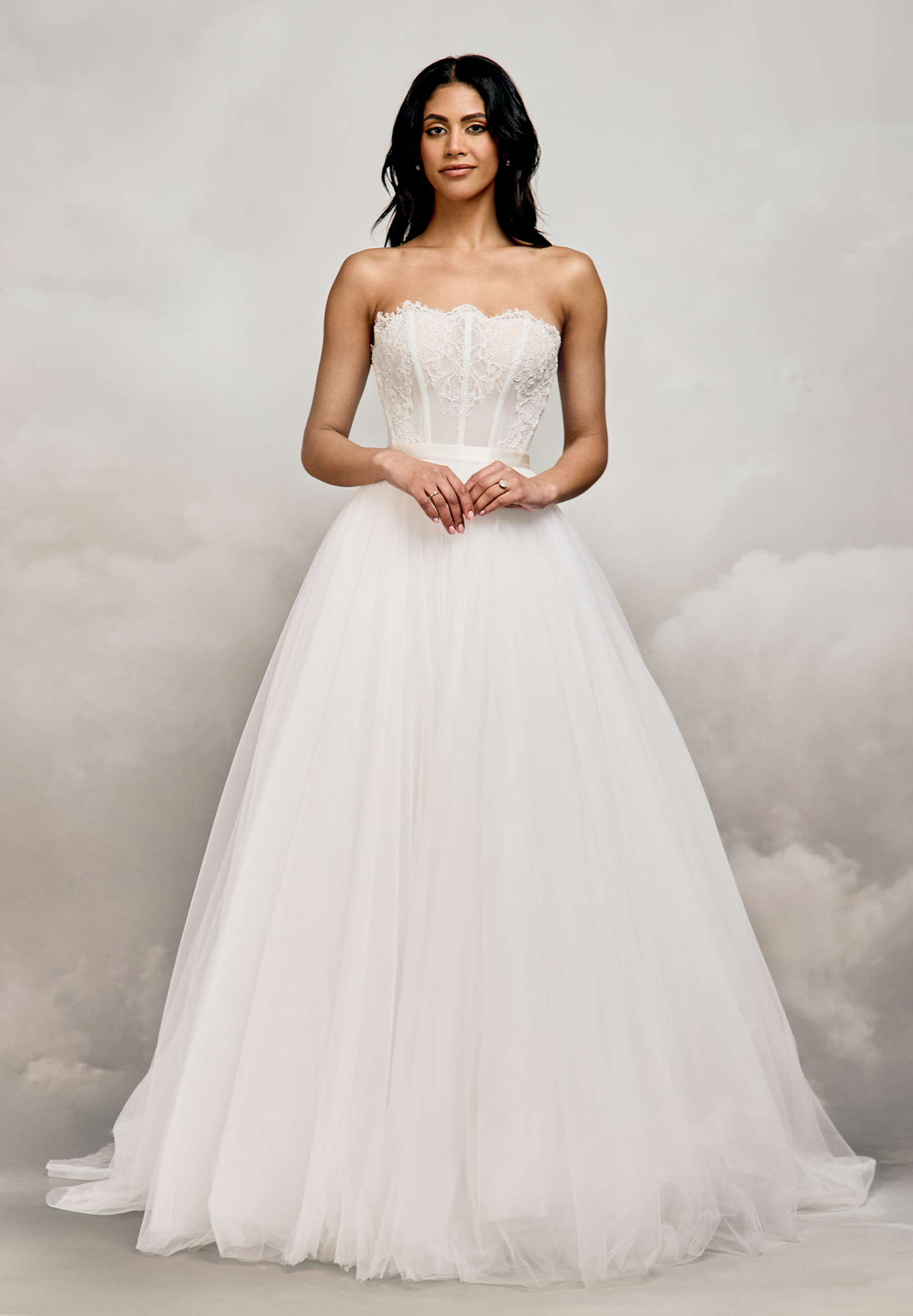 Catherine Deane. Smuk let transparent blonde corsage med snøre i ryggen. Blondetunger i udskæringskanten og tydelige stivere. Corsagen har mulighed for at tilføje en en blød cowl neckline i crepe ogg drapperede off-shoulder ærmer.