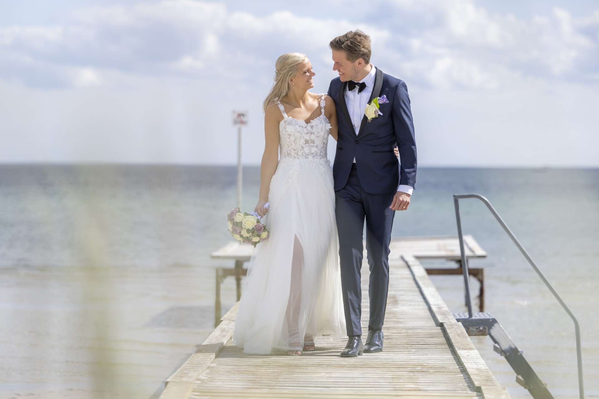 Smuk og romantisk pre-loved brudekjole med masser af 3-D blomster på overkroppen der fader ned på et let og blødt tylskørt. Kjolen har stropper og en skjult slids i skørtet under de yderste tyllag. Meget lidt slæb.
