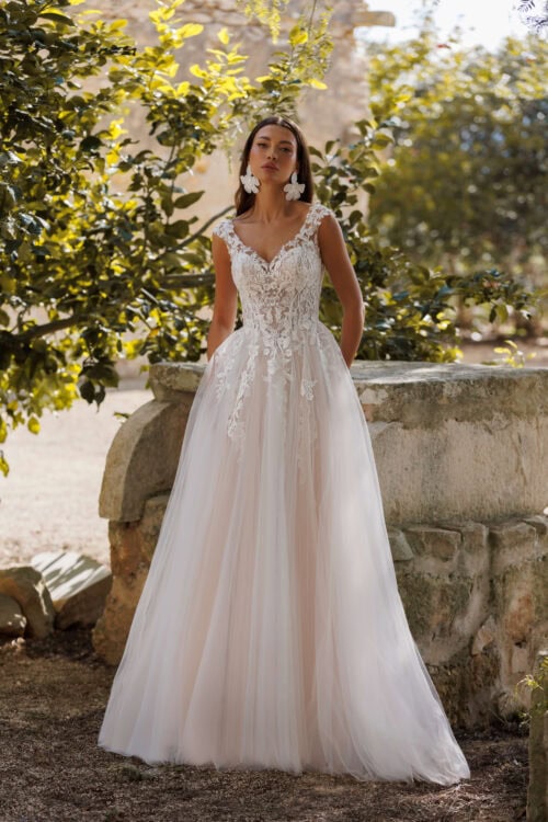 Jarice Bridal - Model Lenette. Smuk romantisk A-line brudekjole med glittertyl. Kjolen har v-udskæring foran og bagpå. Den har blonder på overkroppen som fader ned på skørtet og som danne brede stropper og dække den transperent ryg. Det inderste fór lag er Nude i farven og giver kjolen en varm undertone.