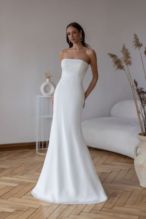 Stropløs og figurnær brudekjole med draperet overdel, dekorativt bælte og glat skørt