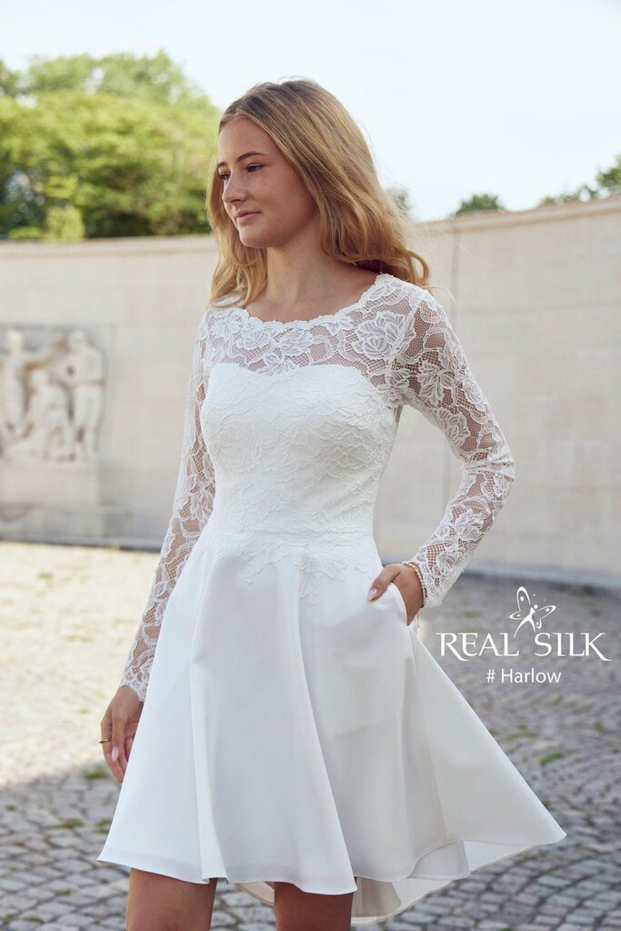 Frontdetalje af Real Silk Harlow konfirmationskjole med rosenblonde, transparente ærmer og glat skørt