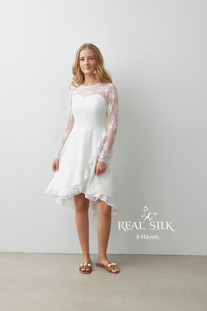 Real Silk Haven konfirmationskjole med transparent blondeærmer, hjerteformet overdel og asymmetrisk flæseskørt