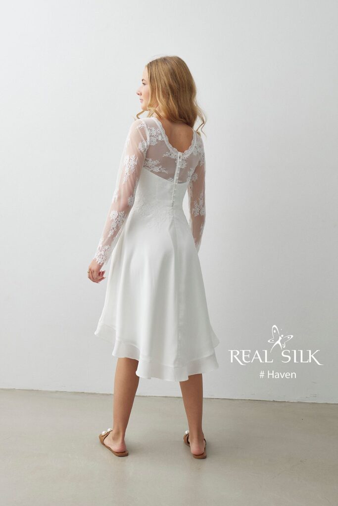 Real Silk Haven konfirmationskjole bagfra med dyb ryg, blomsterblonde, knapper og længere bagstykke