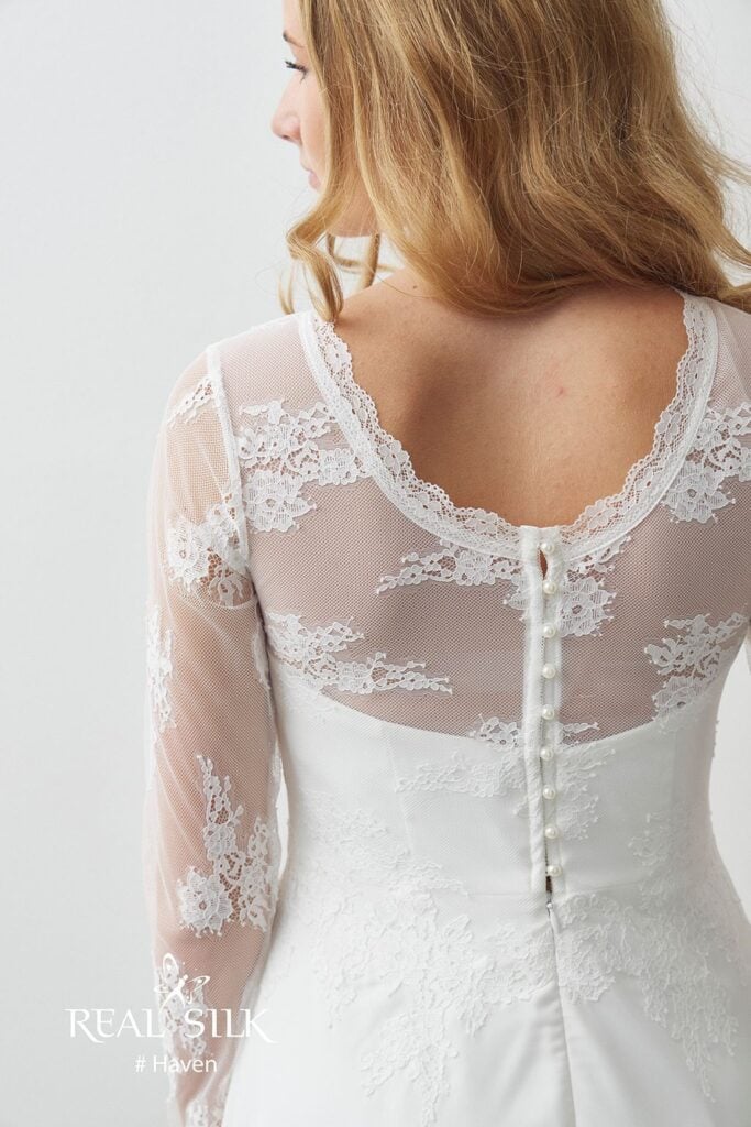Rygdetalje på Real Silk Haven konfirmationskjole med transparent tyl, blomsterblonde og perlelignende knapper