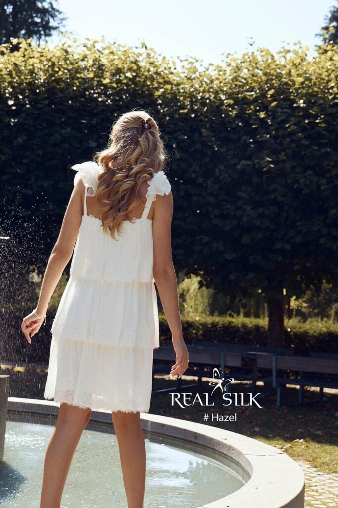 Real Silk Hazel konfirmationskjole bagfra med åben ryg, tynde stropper, skuldersløjfer og lagdelt skørt
