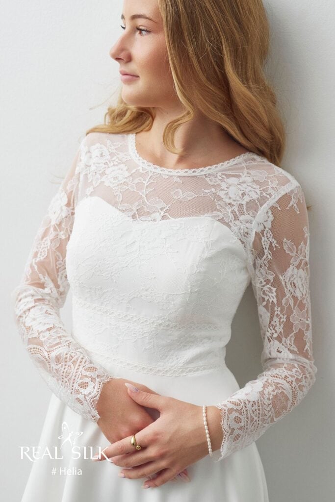Frontdetalje af Real Silk Helia konfirmationskjole med hjerteformet overdel, transparent blomsterblonde og markeret talje