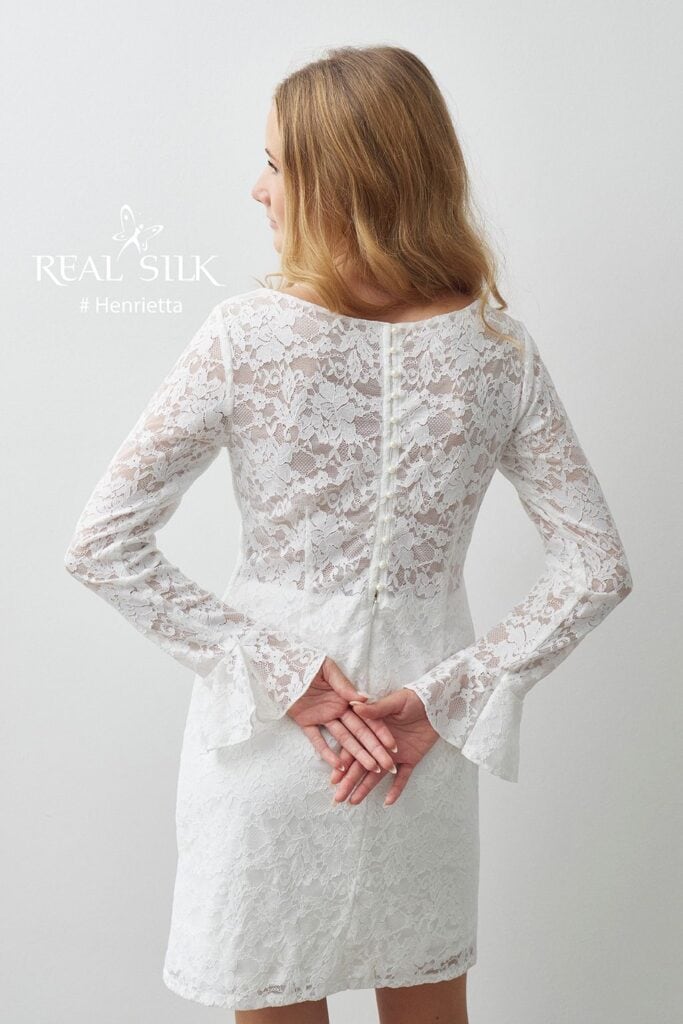 Rygdetalje på Real Silk Henrietta konfirmationskjole med transparent blonde, perleknapper og flæsemanchetter
