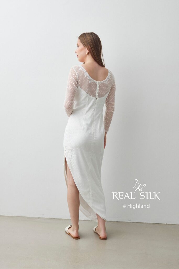 Real Silk Highland konfirmationskjole bagfra med dyb ryg, transparente prikkede ærmer og høj sideslids