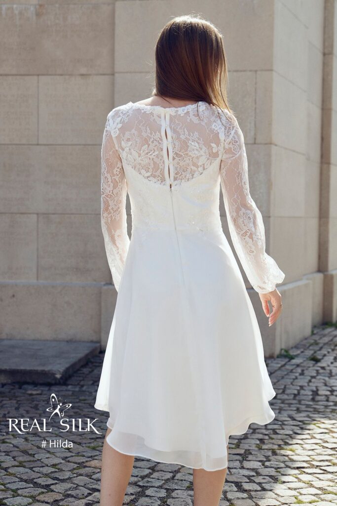 Real Silk Hilda konfirmationskjole bagfra med transparent blomsterblonde, lange ærmer og længere bagstykke