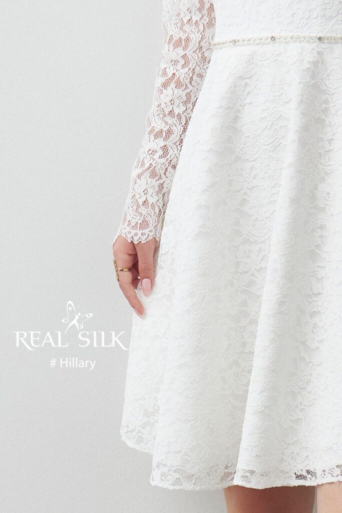 Skørtdetalje på Real Silk Hillary konfirmationskjole med lagdelt blomsterblonde og perlebesat taljekant
